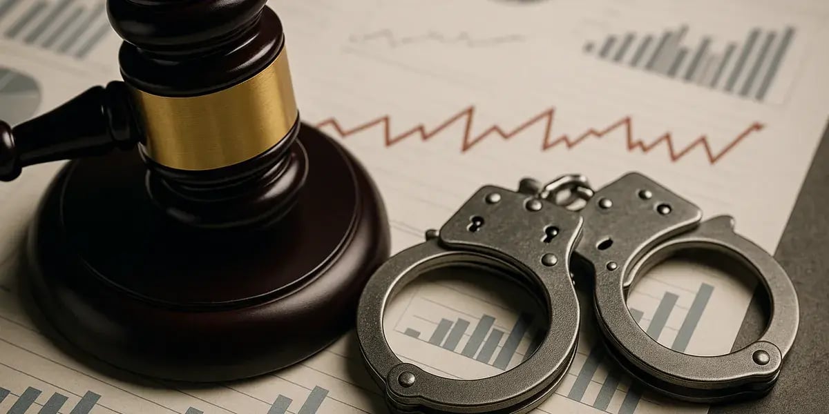 Darstellung von Wirtschaftskriminalität mit Handschellen, Richterhammer und Finanzdiagrammen auf einem Schreibtisch.